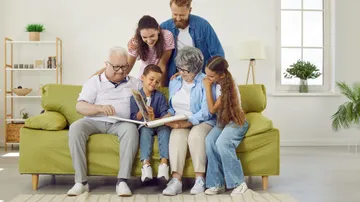 Auf einer Couch sitzen Kinder mit Großeltern dahinter stehen die Eltern