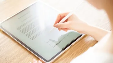Jemand unterschreibt ein Dokument auf einem Tablet.